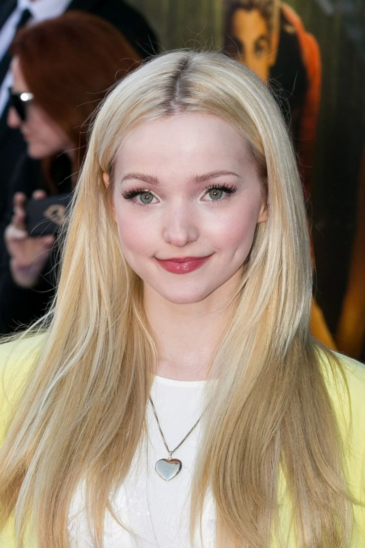 a woman with long blonde hair wearing a yellow jacket