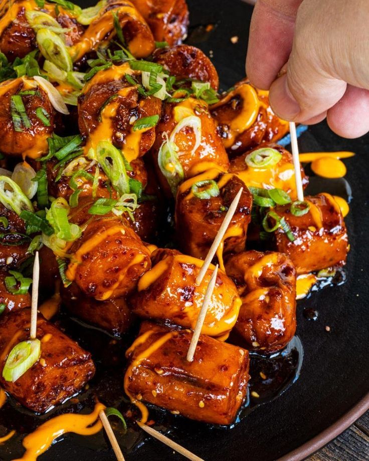 someone is picking up some food from a plate with skewered toothpicks