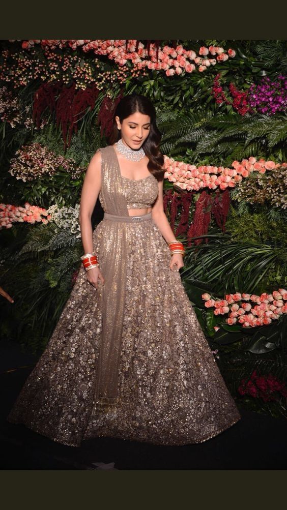 a woman in a gold and silver dress standing next to some flowers on the wall