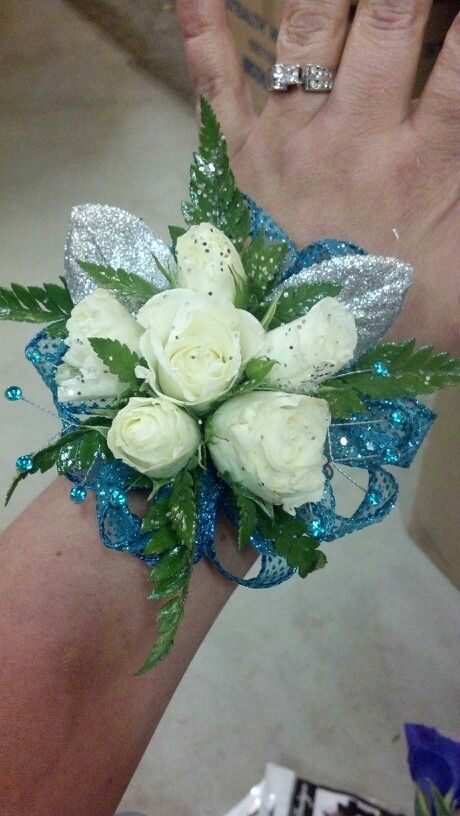 a wrist corsage with white roses and blue sequins on the wrist