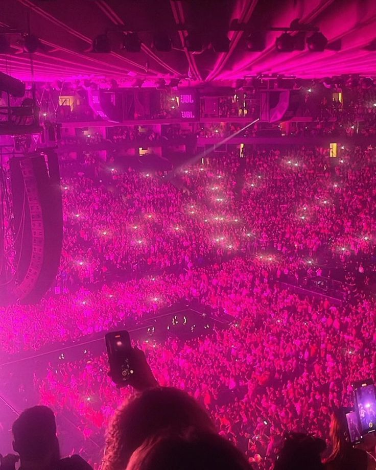 a crowd of people at a concert with their cell phones up in the air and lights on