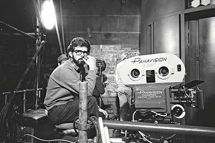 a man sitting on top of a chair next to a movie projector in a dark room