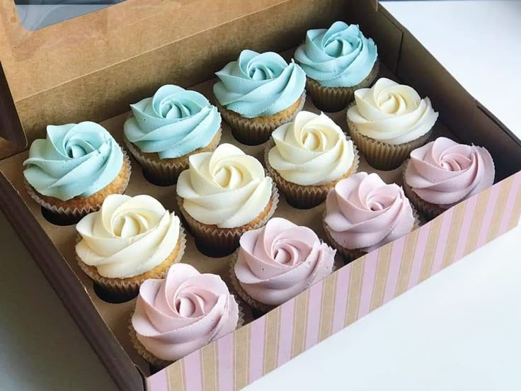 a box filled with lots of cupcakes covered in frosting sitting on top of a table