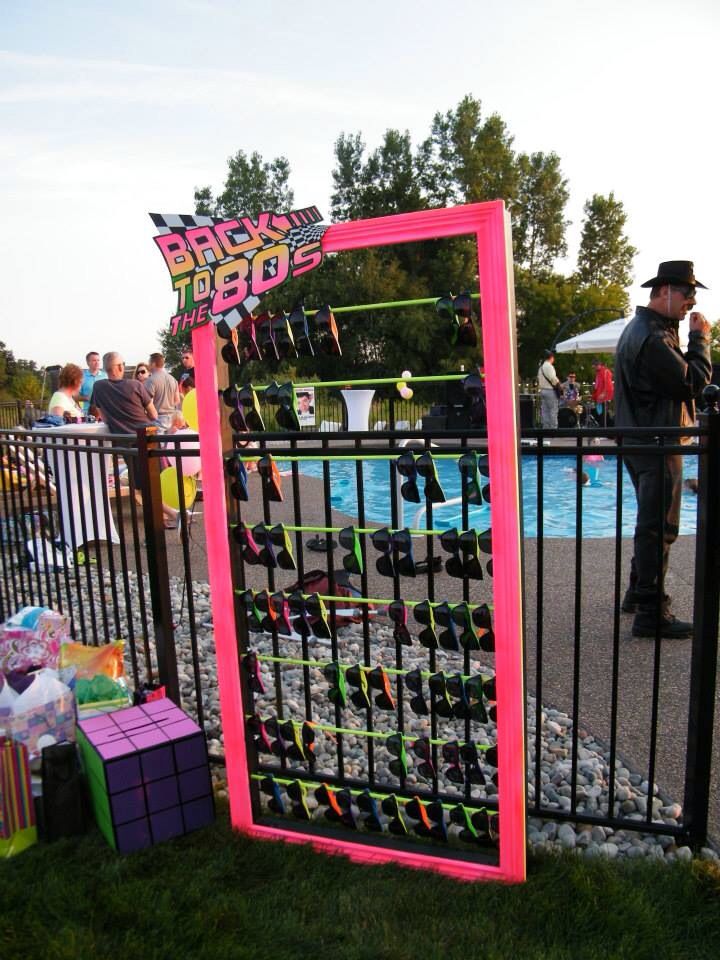 a sign that is on the side of a fence near a pool with people standing around it