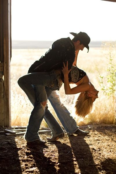 a man and woman are dancing in the barn together with cowboy hats on their heads