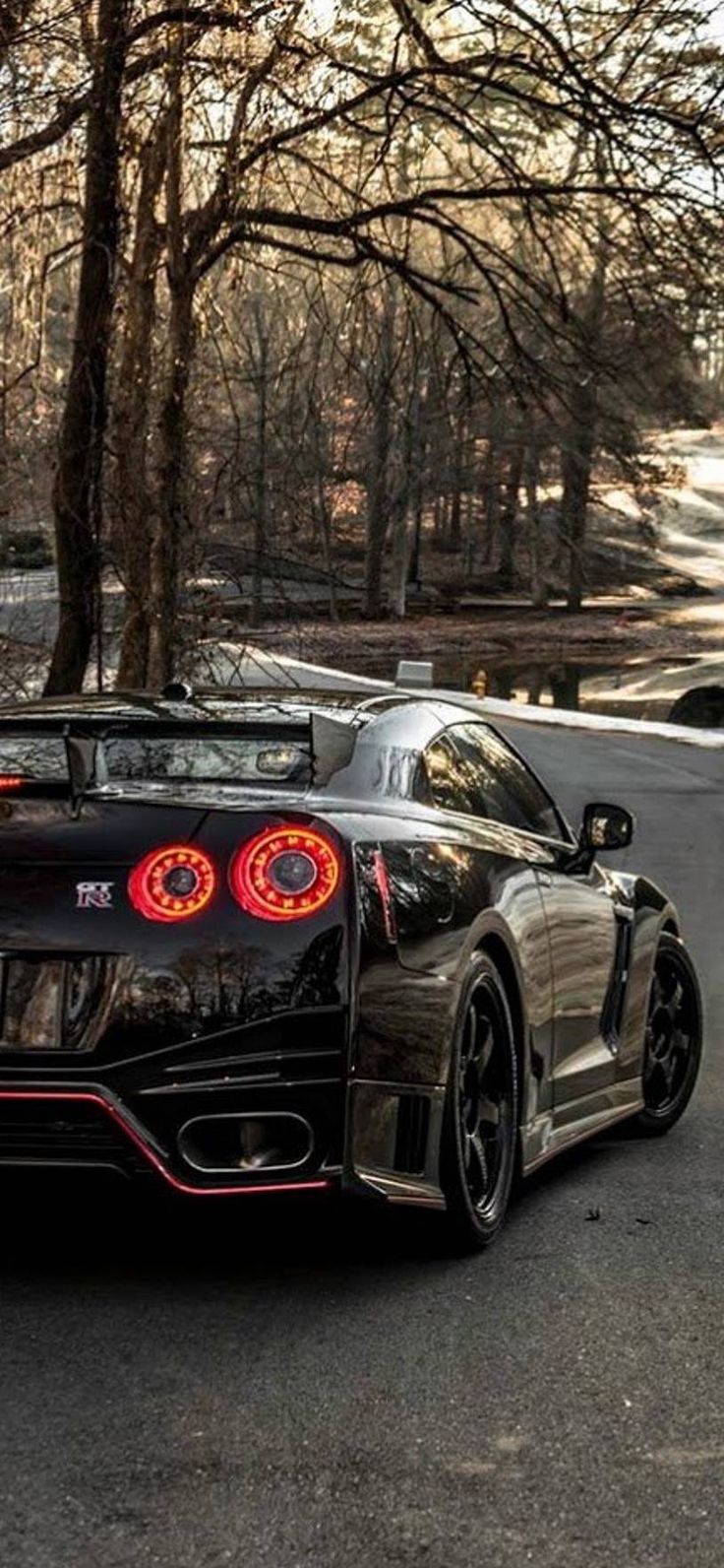 a black sports car is parked on the side of the road in front of some trees