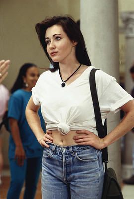 a woman standing with her hands on her hips and looking at the camera while others stand in line