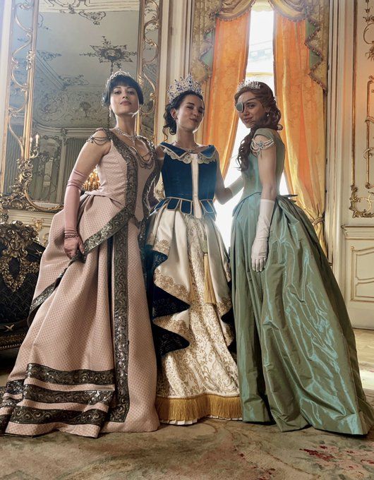 three women in period dresses standing next to each other