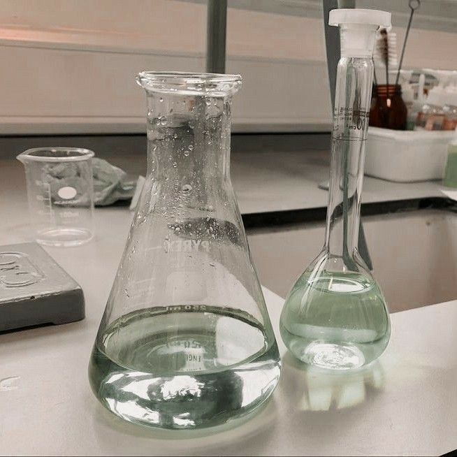 two flasks filled with liquid sit on a table