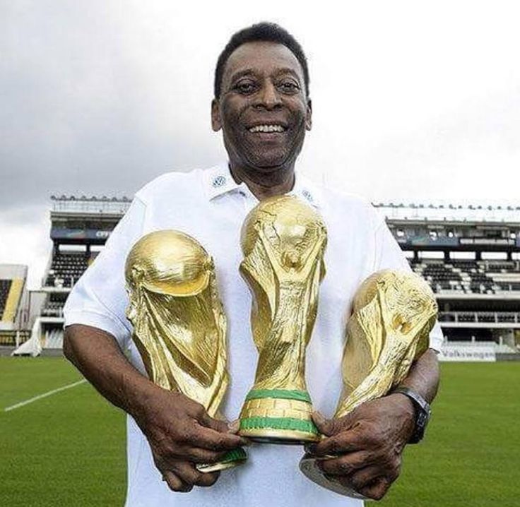 a man holding three golden soccer trophies in his hands