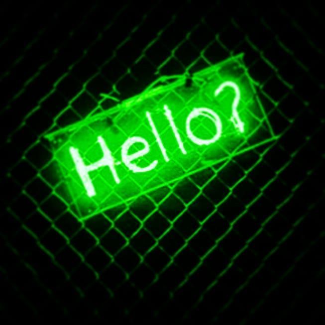 a green neon sign that says hello? on the side of a wire mesh fence