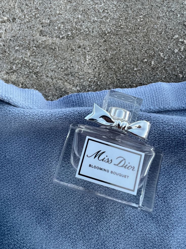 a bottle of miss dior cologne sitting on top of a blue towel with a bow