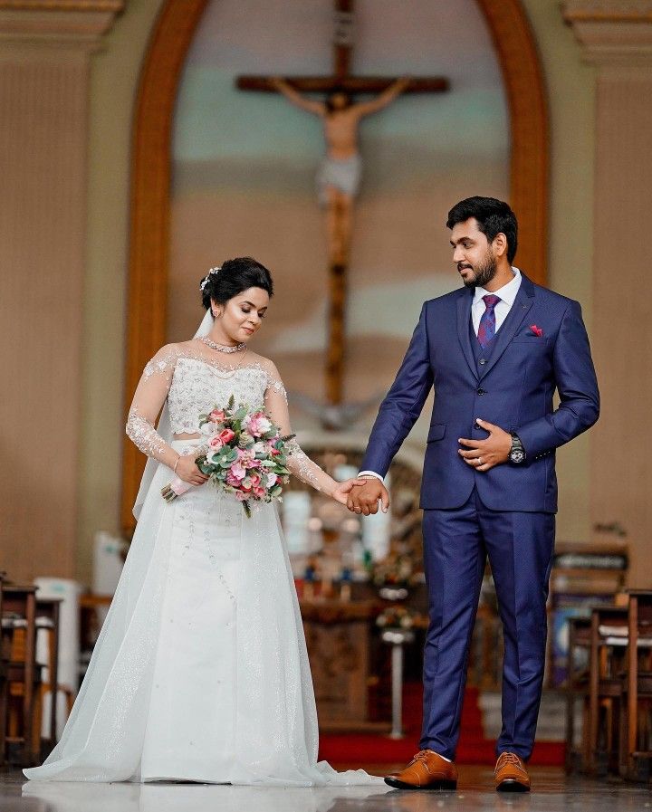 a bride and groom holding hands in front of the alter at a wedding ceremony with a crucifix behind them