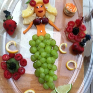 a tray with grapes, strawberries, oranges and other fruits arranged on it