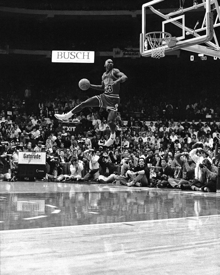 an old black and white photo of a basketball player jumping up to dunk the ball