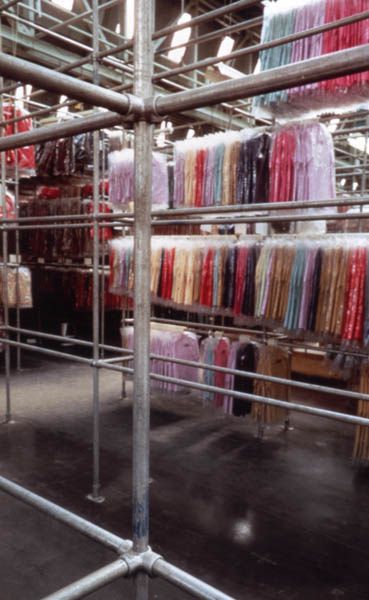 the inside of a clothing store filled with lots of different colored shirts and ties on racks