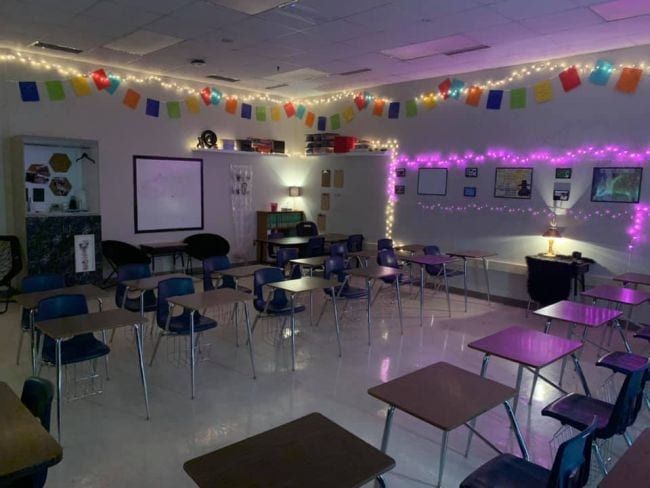 an empty classroom with desks, chairs and lights on the ceiling is lit up