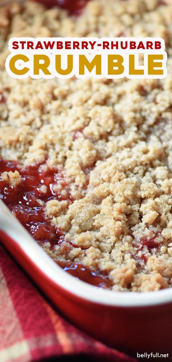 strawberry rhubarb crumble is in a red dish on a checkered table cloth