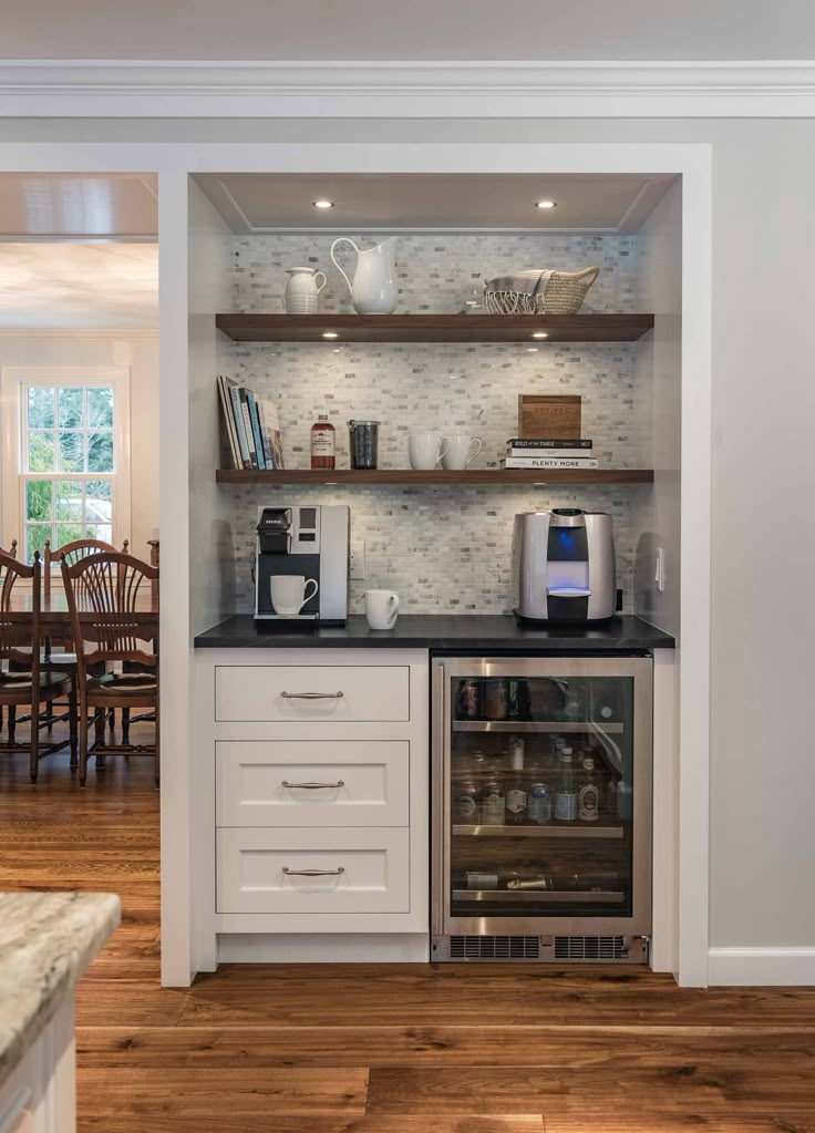 a kitchen with white cabinets and black counter tops, an oven and coffee maker in the corner