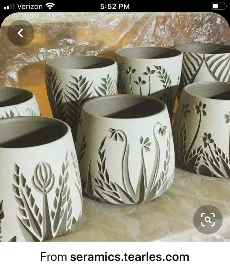 several white vases with black designs on them