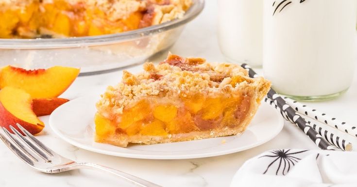 a slice of peach pie on a plate next to a glass of milk