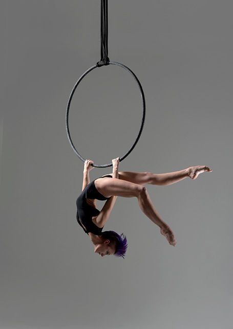 a woman is doing aerial acrobatics on a hoop