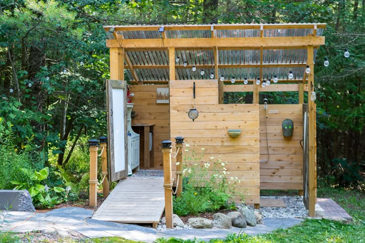 a wooden outhouse in the middle of a wooded area with stairs leading up to it