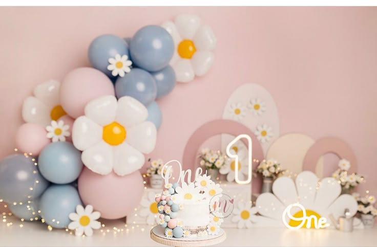 a birthday cake sitting on top of a white table next to balloons and flowers in the background