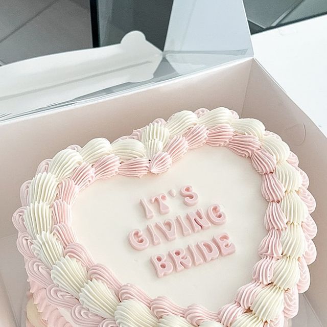 a heart shaped cake with the words it's giving bride written in frosting