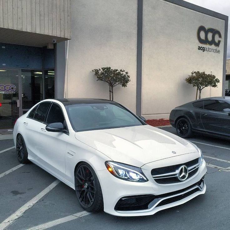 a white mercedes benz is parked in front of a car dealership with other cars