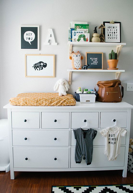 a baby's room with white dressers and pictures on the wall above it