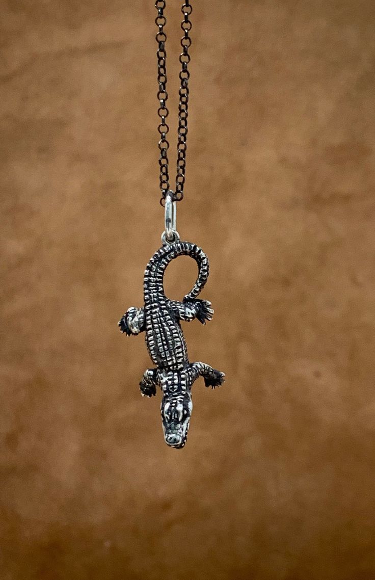 This  crocodile Necklace is handmade in 925 sterling silver by Pamanova  in U.S.A. It is antiqued by oxidizing and polished to show the details of the design. This necklace is the perfect gift for yourself or a loved one, ideal for men and women, young and old. Size:  - The crocodile size : Approximately 1.35 inches long (34 mm) by 0.60 inched wide (15 mm )   -  The total length of chain is 18 inches. Cartier Crocodile Necklace, Crocodile Earrings, Crocodile Necklace, Alligator Accessories, Silver Gothic Chain Necklace With Lobster Clasp, Gift For Men, Jewelry Necklace, Reptiles, Alligator