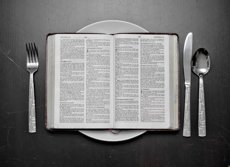 an open book sitting on top of a table next to silverware