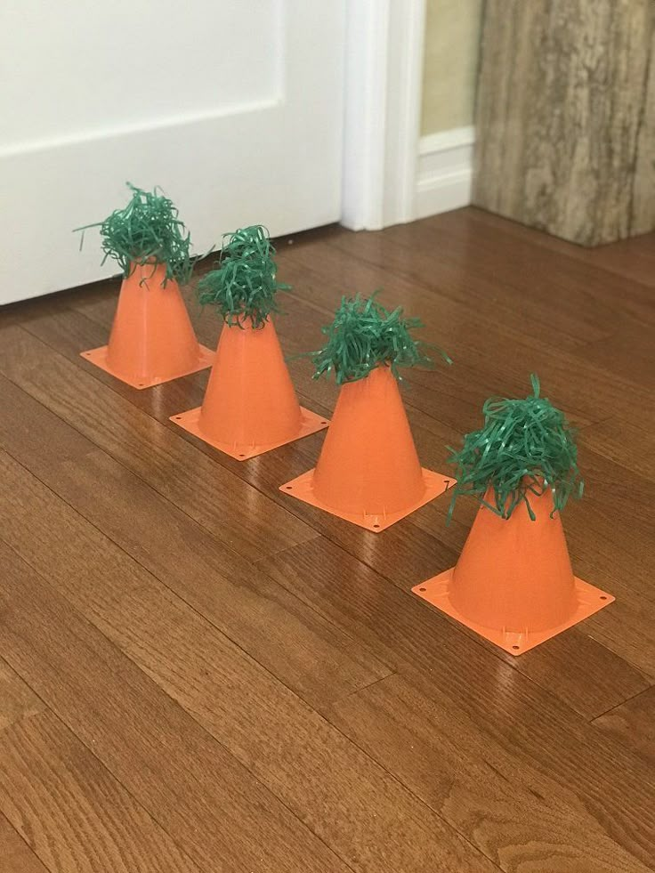 four small orange cones with green plants on them sitting on the floor in front of a door