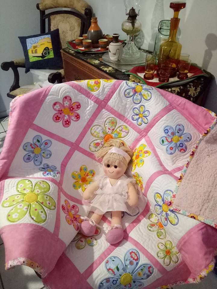 a teddy bear sitting on top of a pink and white quilt in a living room