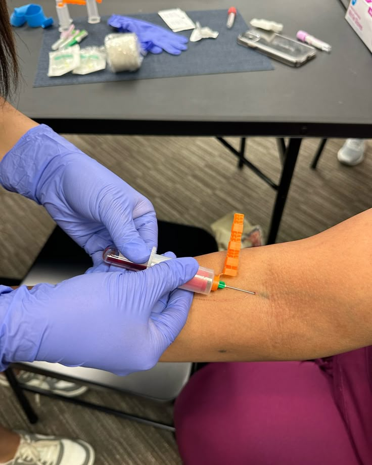 a person in purple gloves is getting an injection from another person's arm,