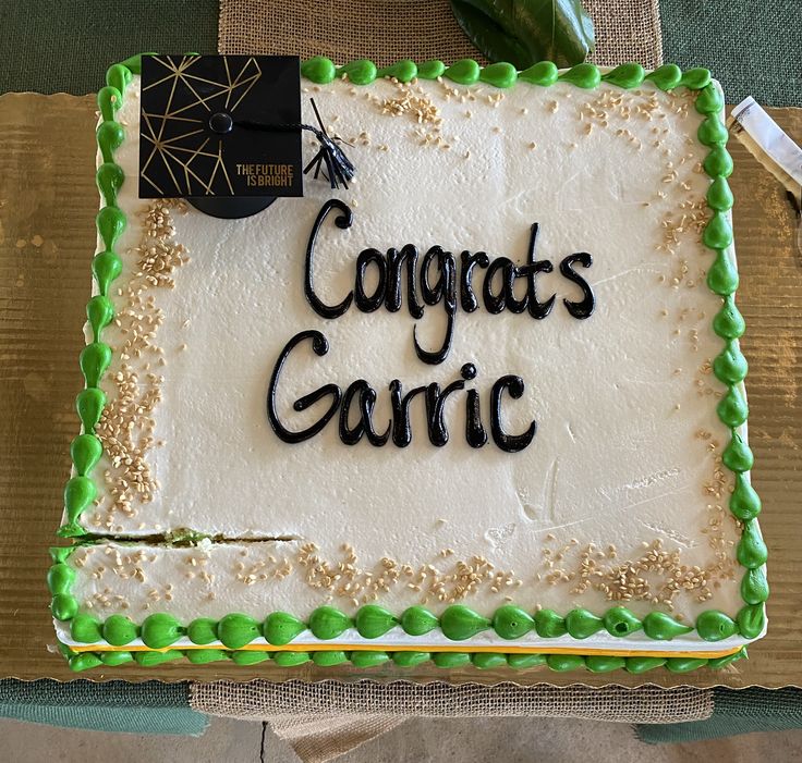 a cake that says congrat's garlic on it with green frosting and gold sprinkles