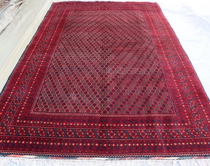 a large red rug sitting on top of a bed next to a white sheet covered floor