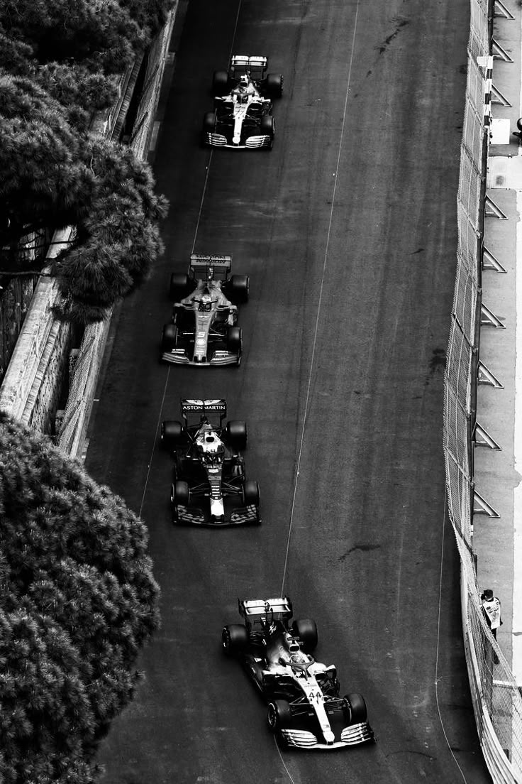 black and white photograph of race cars driving down the track