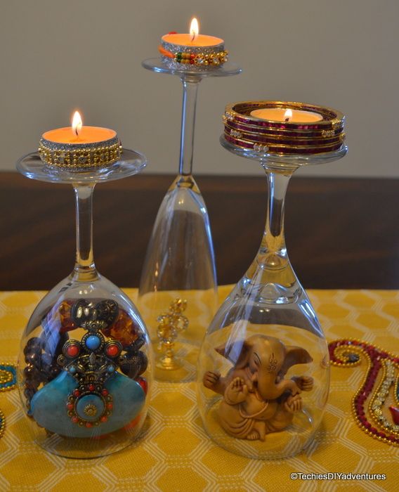 three wine glasses with candles in them on a yellow table cloth and some glass vases