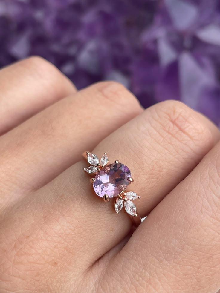 The immaculate vibes of our Contessa Ring are absolutely unmatched. ✨ The pristine and opulent amethyst crystal is framed by two delicate cubic zirconia blossoms in this delicate design. Delicate and regal, unique yet versatile, the Contessa Ring is a unique and stunning addition to any jewelry collection. 💜 * * * Don't know your ring size? View our Ring Size Guide * * * …………………………………. RING SIZE & MATERIAL❋ 18k rose gold plated sterling silver❋ cubic zirconia crystals❋ 6x8mm natural amethyst cr Amethyst Wedding Rings Gold, Cristal Engagement Ring, Gold Ring With Amethyst, Rings Engagement Amethyst, Purple Gem Engagement Ring, Amathus Ring, Jewel Rings Gems, Purple Sapphire Engagement Ring Stacking, Ring Designs Silver Unique