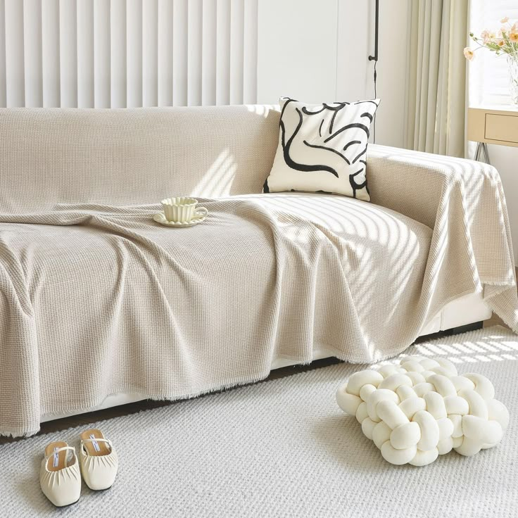 a living room with a couch covered in a blanket and slippers on the floor