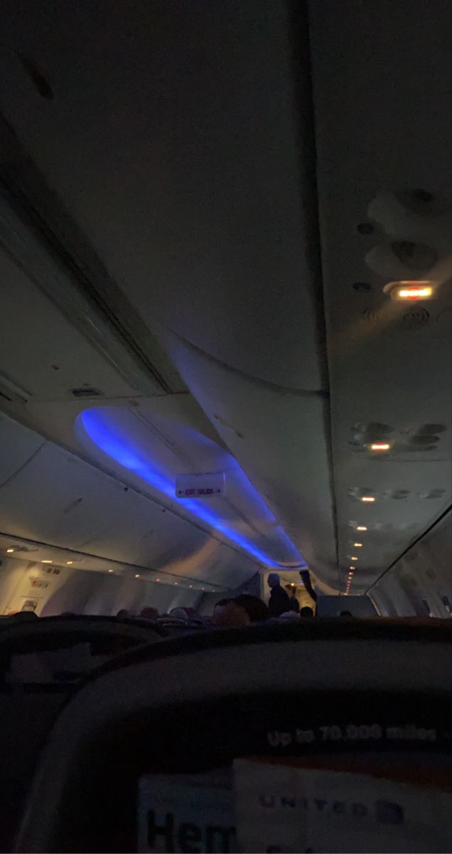 the inside of an airplane with blue lights and people sitting in seats on either side