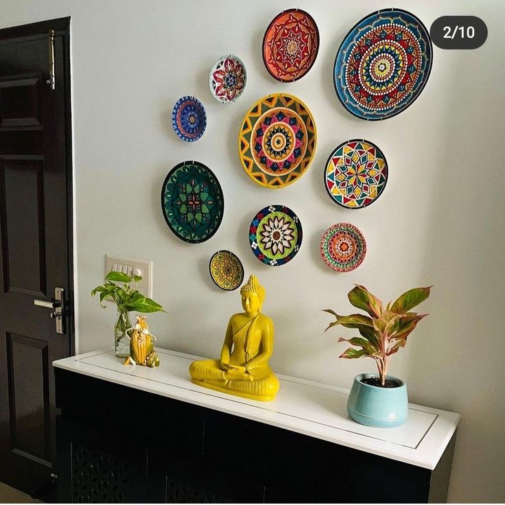 there are many plates on the wall and one has a buddha statue next to it