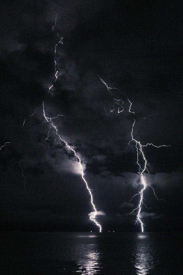 black and white photograph of lightning striking over the ocean