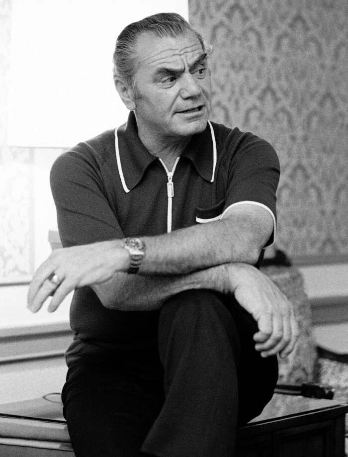 a man sitting on top of a table with his arms crossed and looking off to the side