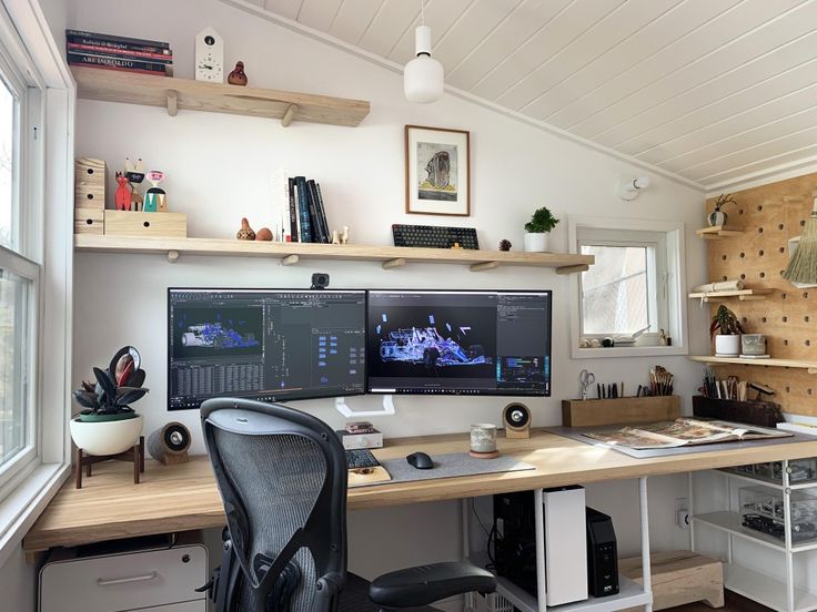 two computer monitors sitting on top of a wooden desk