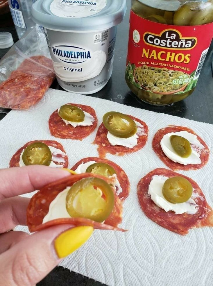 a person is making appetizers with olives and cheese on them, along with other ingredients