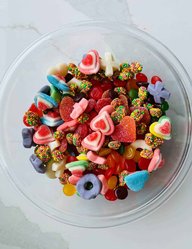 a glass bowl filled with lots of colorful candies on top of a white counter