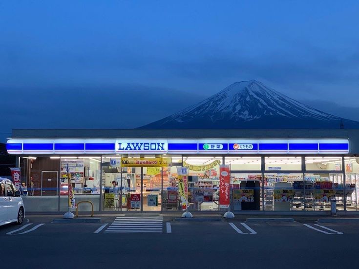 an empty parking lot in front of a convenience store with a mountain in the background